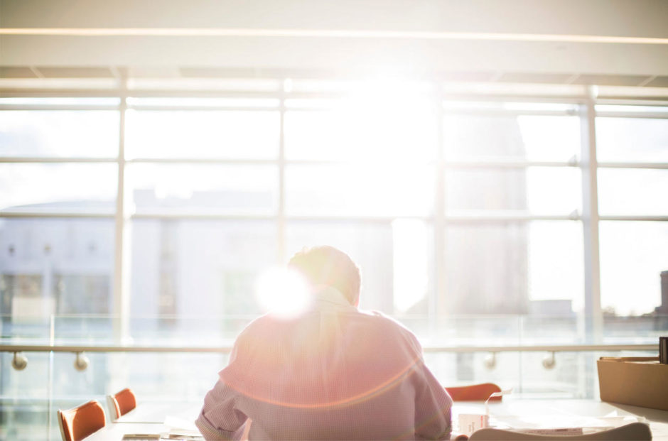 The-Ultimate-Guide-to-Hiring-Remote-Employees The-Ultimate-Guide-to-Hiring-Remote-Employees-man-at-desk-in-sunshine