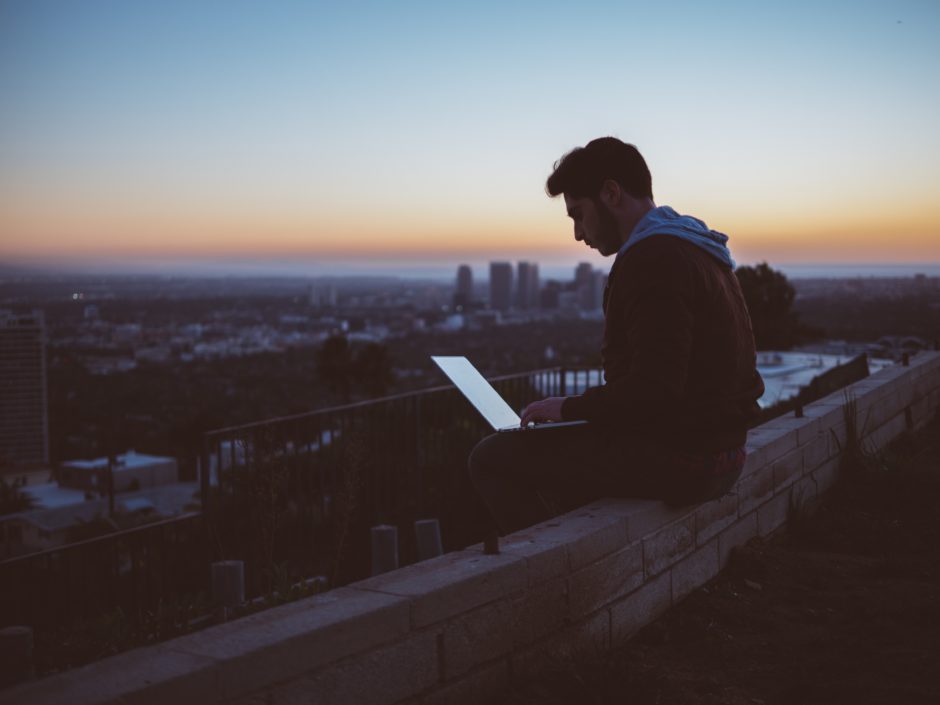 avi-richards-183715.jpg Man sitting on rooftop, looking at his tablet